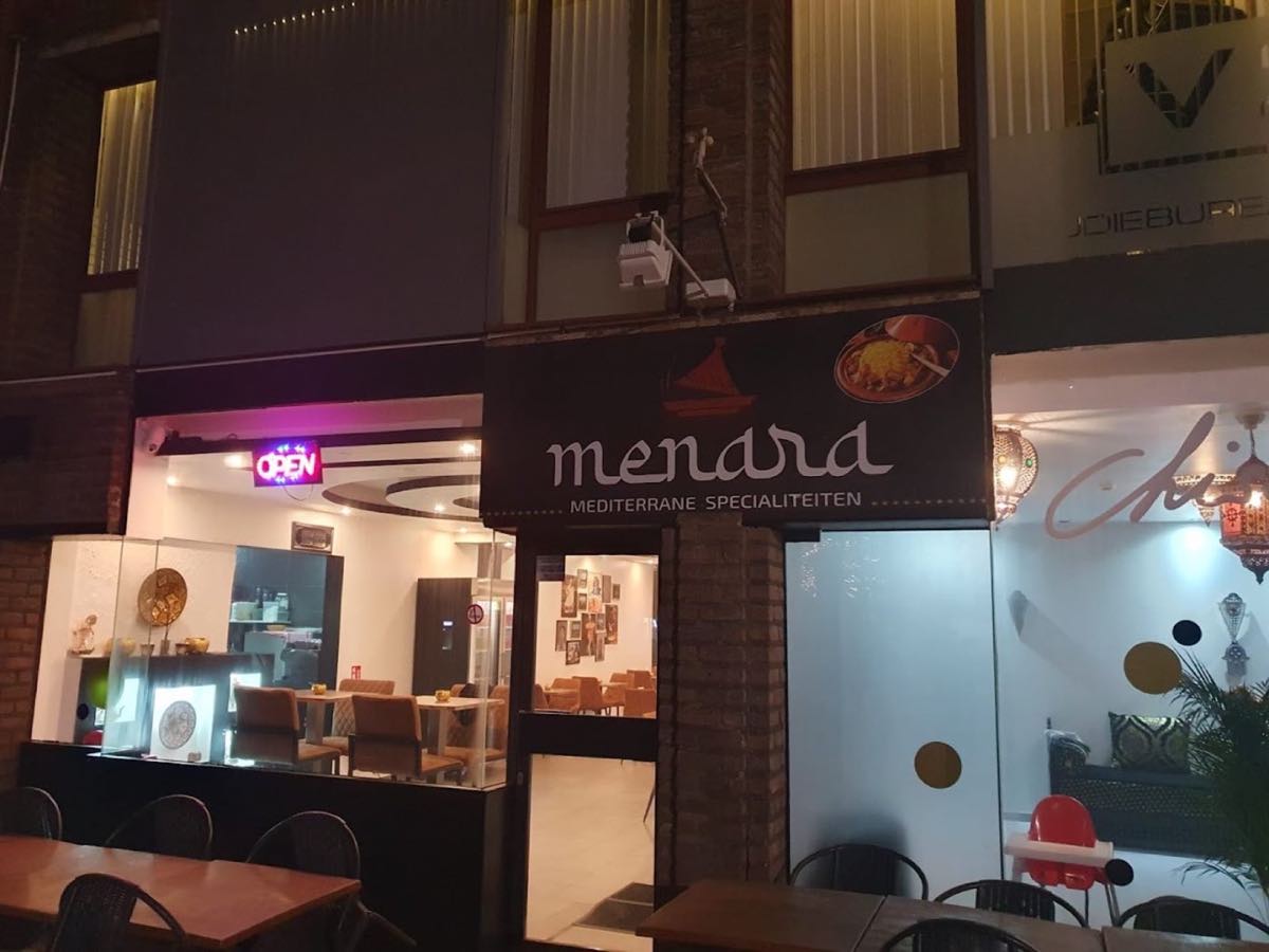 De verlichte gevel van restaurant Menara in Genk bij avond